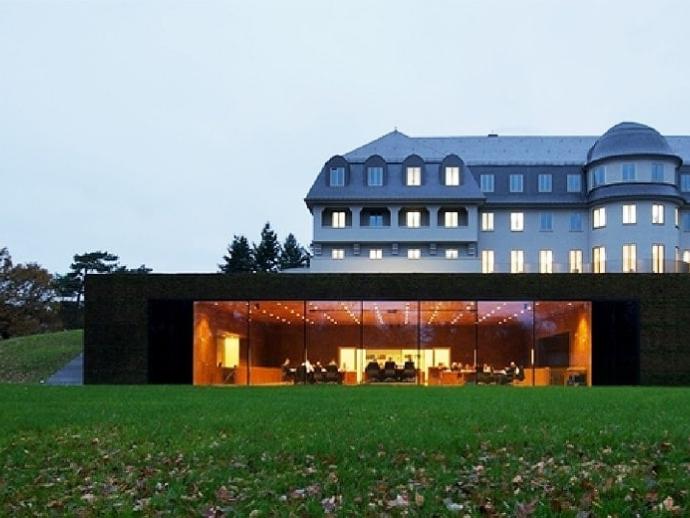 Außenansicht des Parlamentsgebäudes, ein ehemaliges Sanatorium aus dem Jahr 1915 mit einem vorgebauten Plenarsaal mit Glasfront.