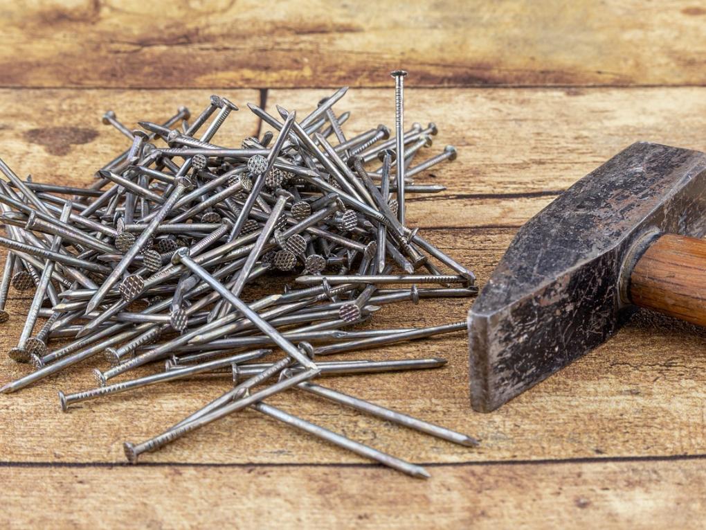 Links liegen einige Nägel neben einem Hammer (rechts im Bild).
