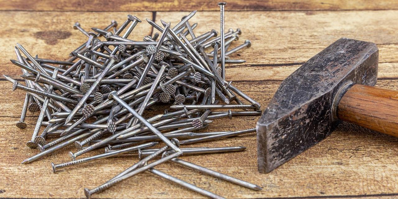 Links liegen einige Nägel neben einem Hammer (rechts im Bild).