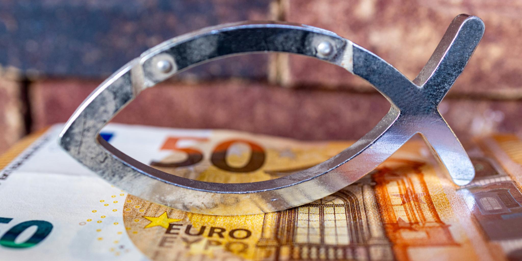 Das christliche Symbol eines Fisches ist aus Metall in zwei schlichten Linien gebildet. Es steht auf einem 50-Euro-Schein.