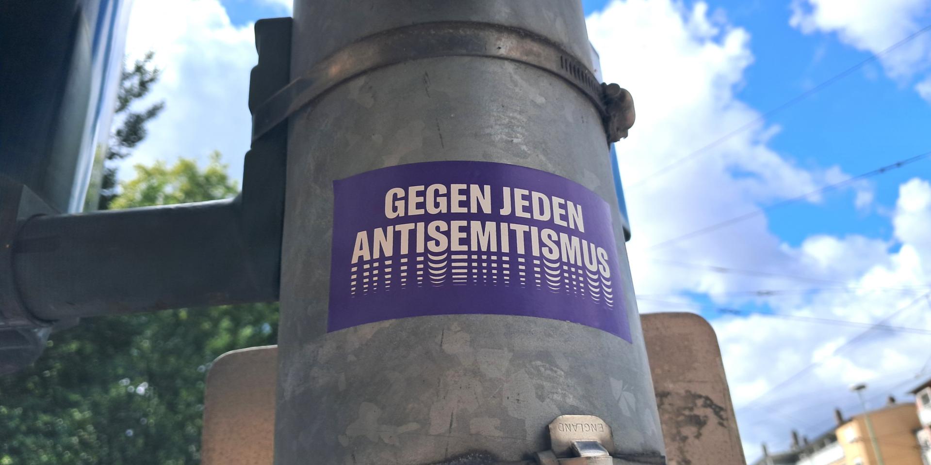 Aufkleber auf einer Straßenlaterne: 'Gegen jeden Antisemitismus.'