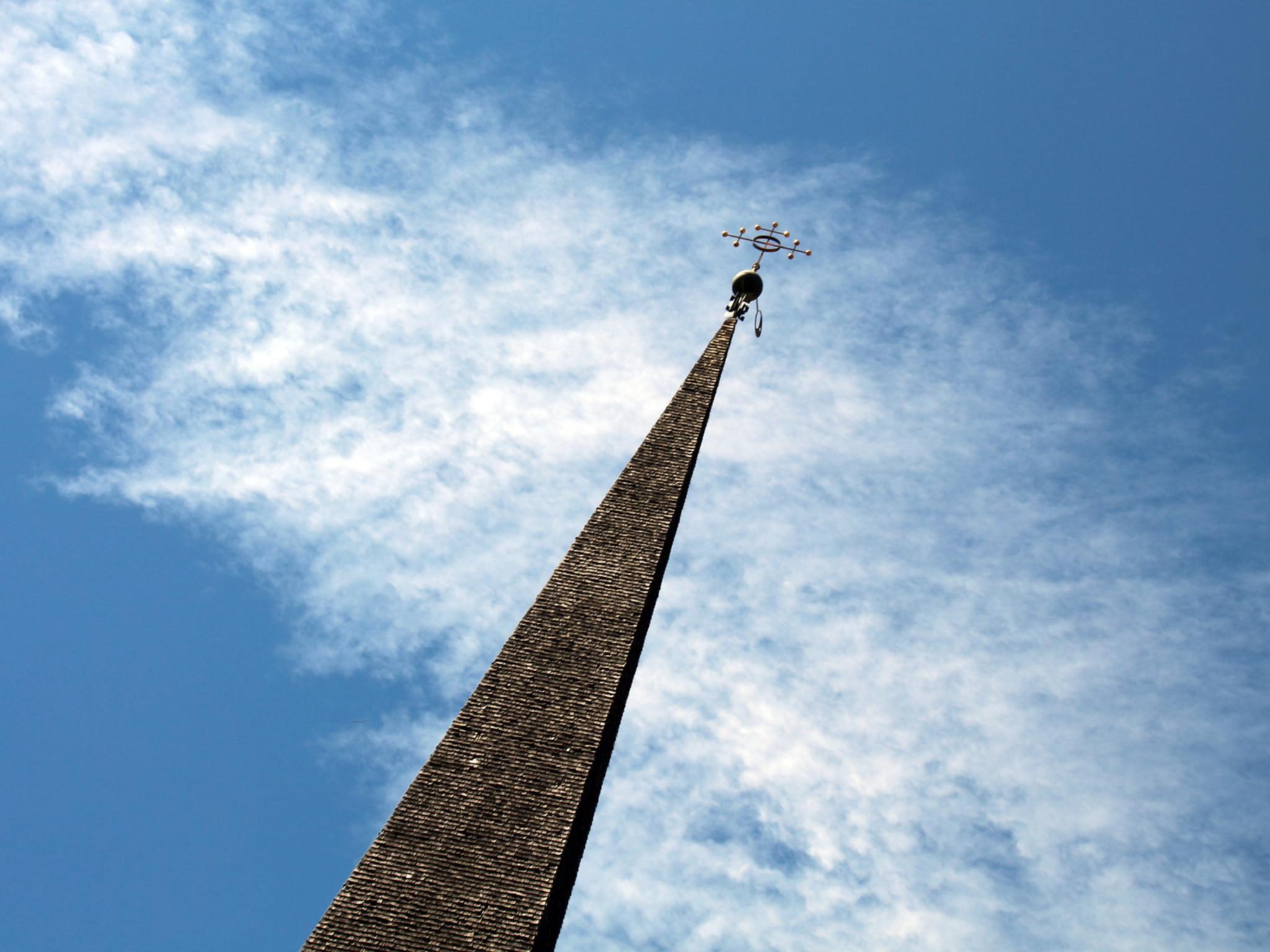 Kirchturm ragt vor dem Himmel auf, in der Perspektive ist er nach rechts geneigt.