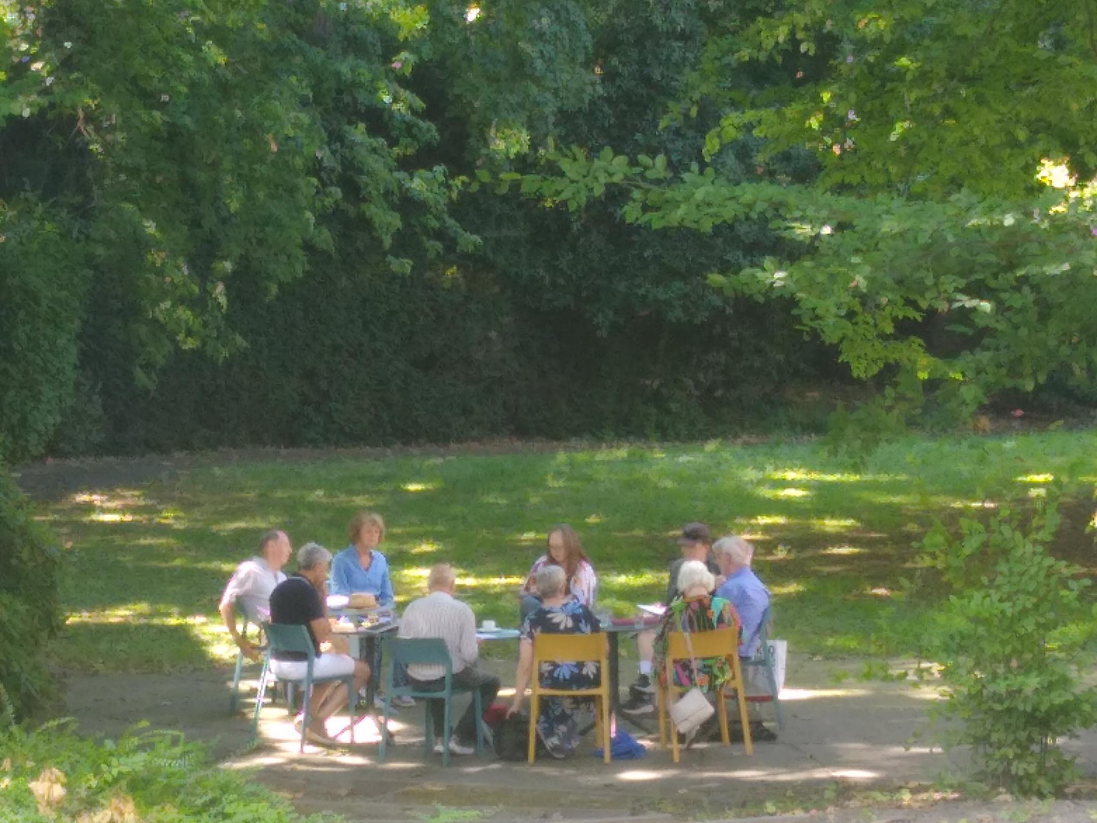 Die Arbeitsgruppe eines Seminars sitzt unter Bäumen im Schatten und arbeitet an einem Bibeltext.