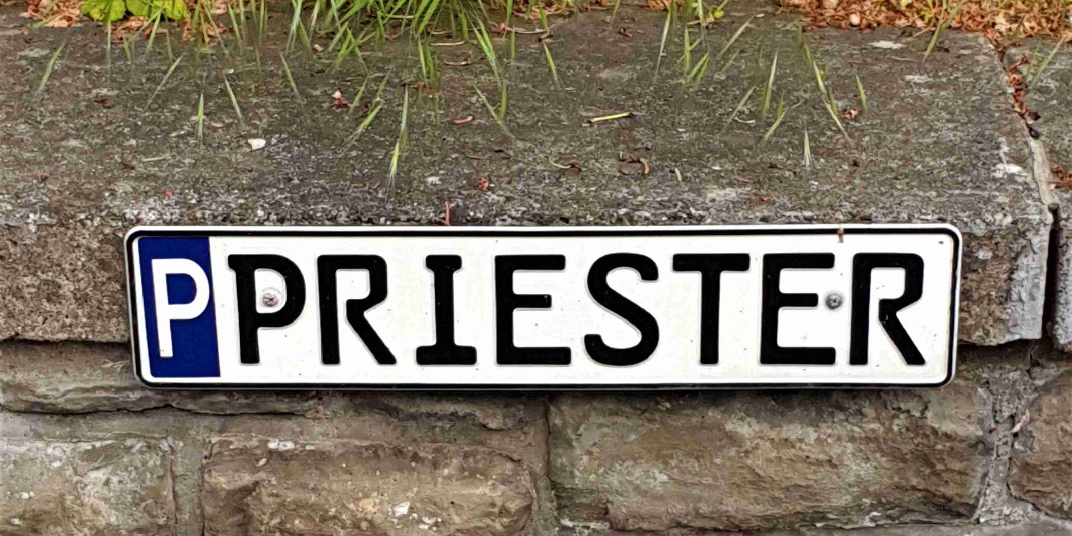 Ein Schild weist einen Parkplatz für den Priester aus.