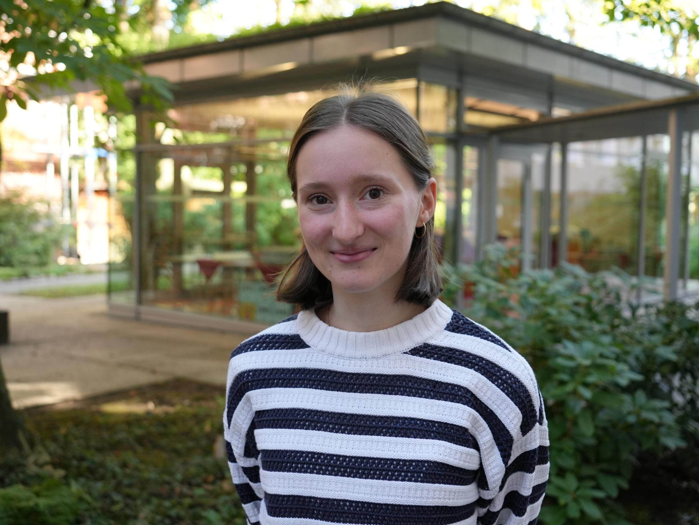 Eine junge Frau vor dem Gartenpavillon der Akademie.