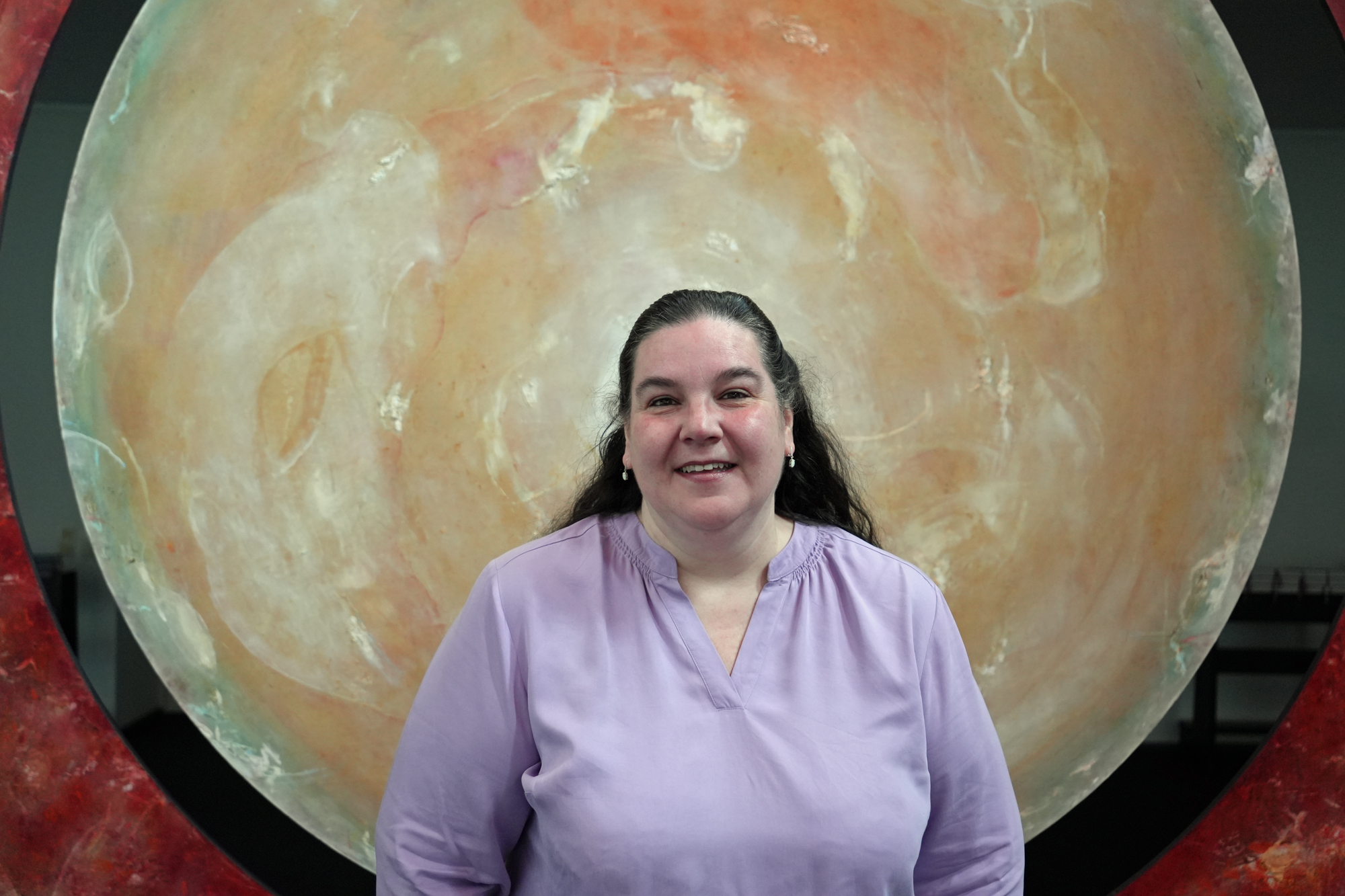 Eine Frau steht vor einer goldenen Scheibe.