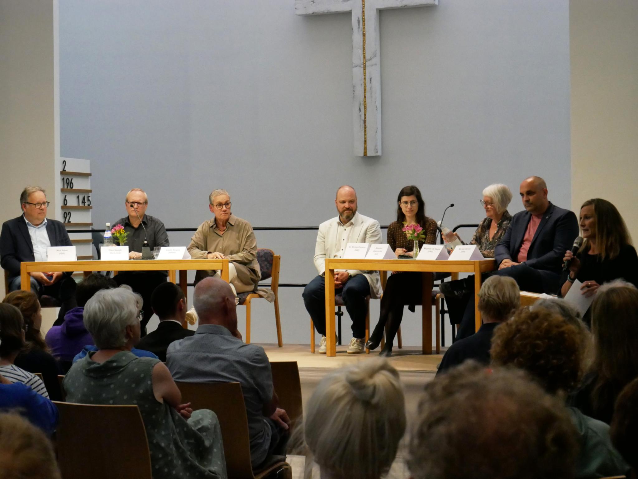 Personen, die bei der Kommunalwahl für das Amt des Oberbürgermeisters, der Oberbürgermeisterin kandidieren, an Tischen.
