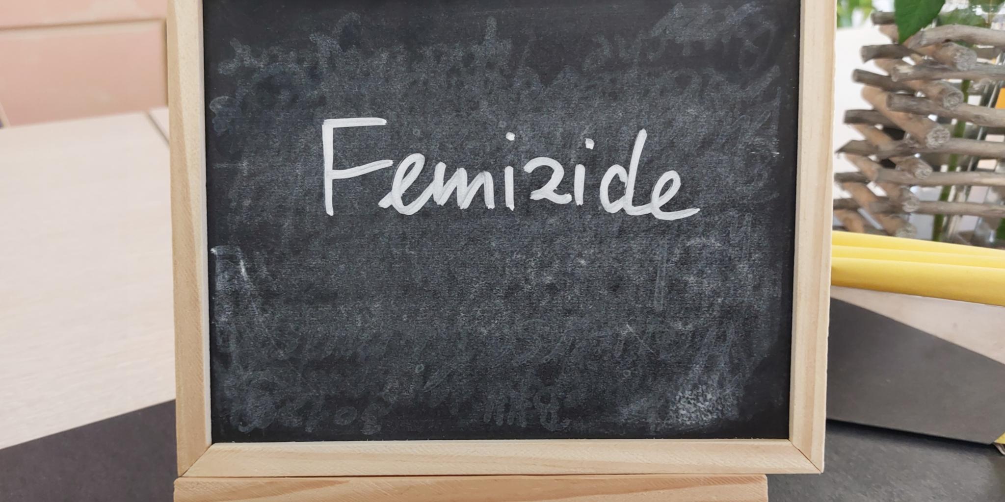 Schiefertafel mit der Aufschrift 'Femizide' auf einem Tisch