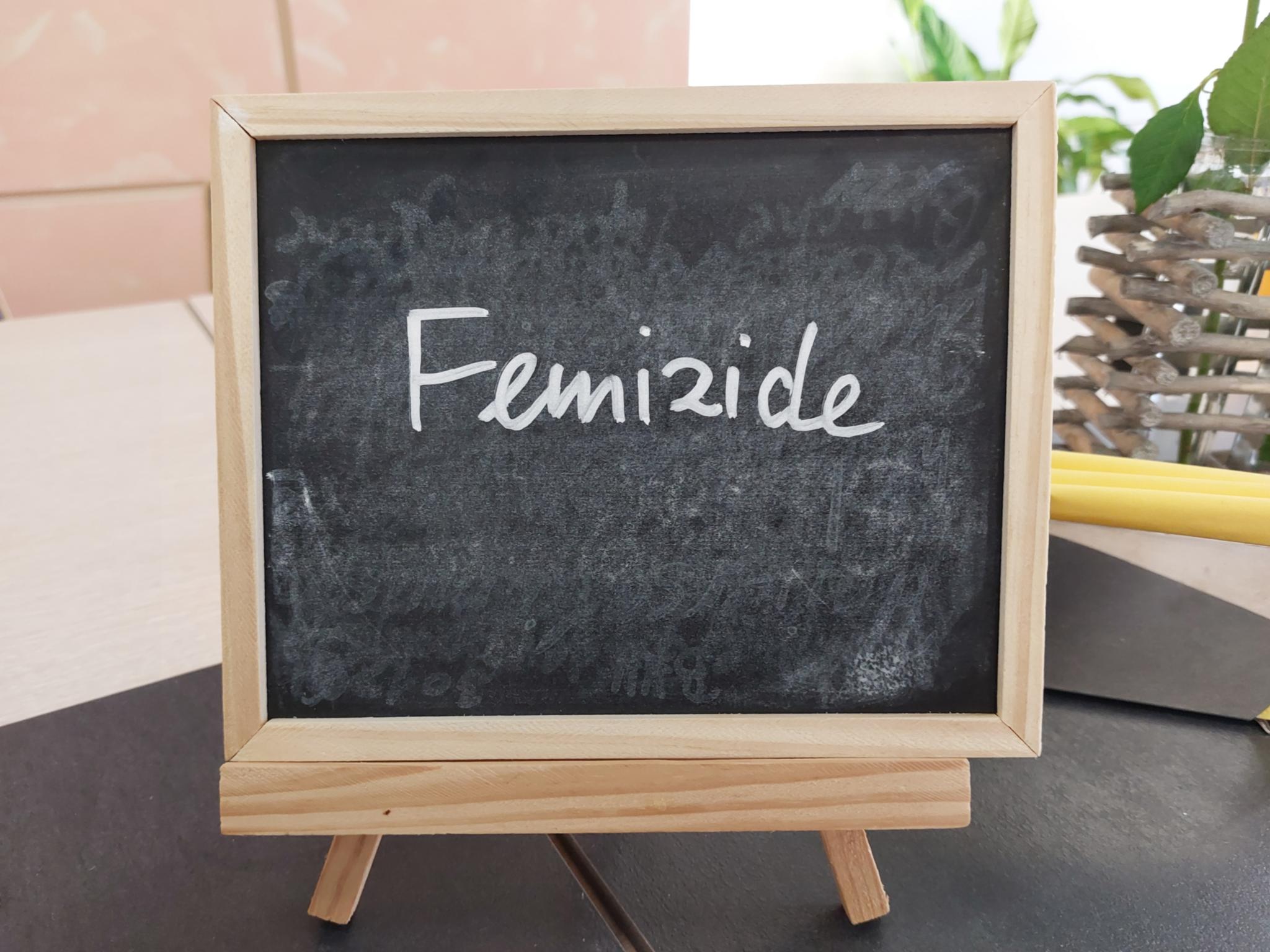 Schiefertafel mit der Aufschrift 'Femizide' auf einem Tisch