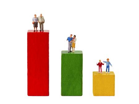 Drei Bauklötze, von links nach rechts in absteigender Größe, darauf links ältere Menschen in der Mitte mittelalte Menschen, auf dem kleinsten Bauklotz Kinder.