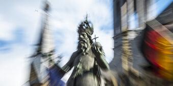 Verwischtes Bild der Statue Kaiser Karls vor dem Aachener Rathaus mit Europaflagge und Deutschlandflagge)