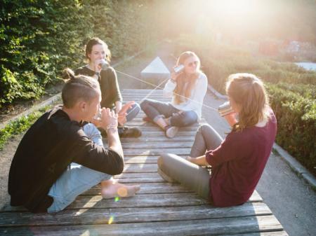 Junge Menschen sitzen in einer Gruppe auf dem Boden und unterhalten sich.