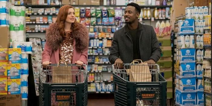 Eine Frau und ein Mann schieben jeweils einen Einkaufswagen durch einen Supermarkt.