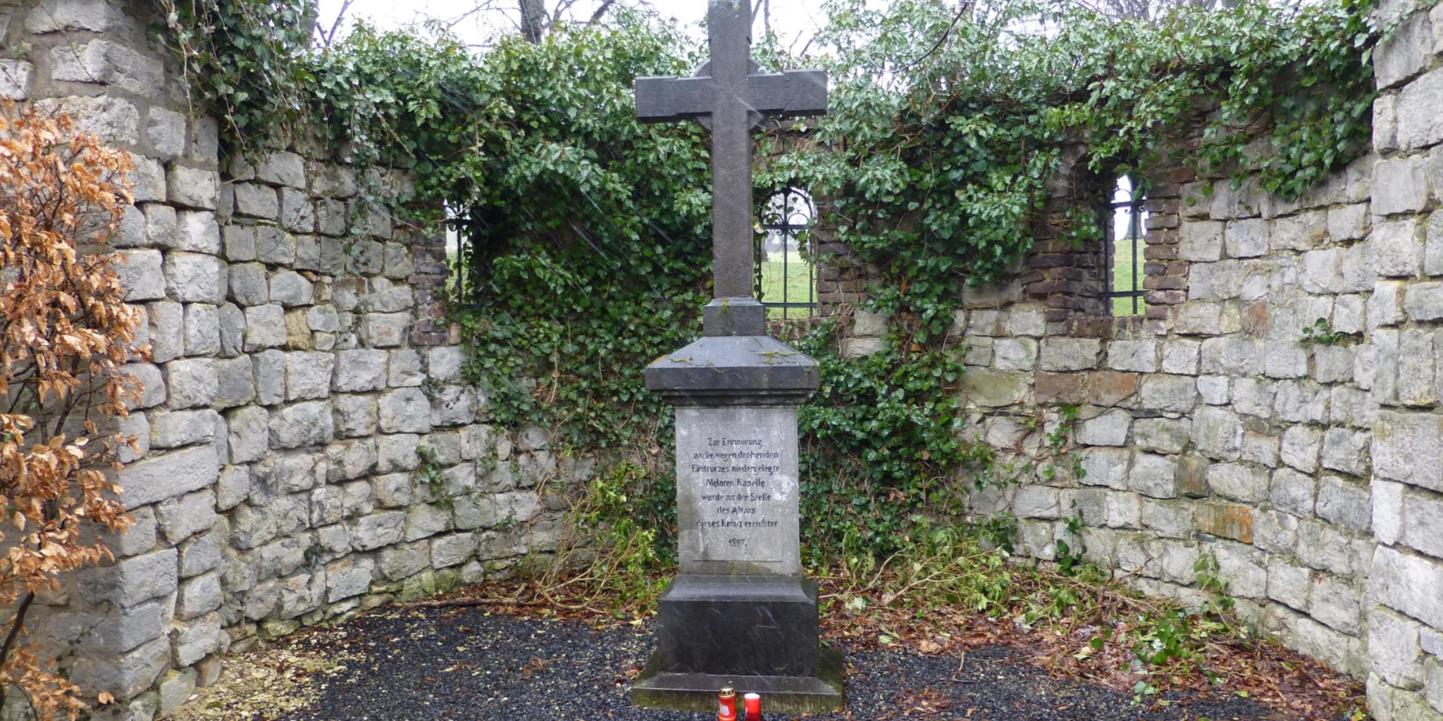 Wegekreuz aus Stein in einer gemauerten Nische am Jakobsweg Gulpen