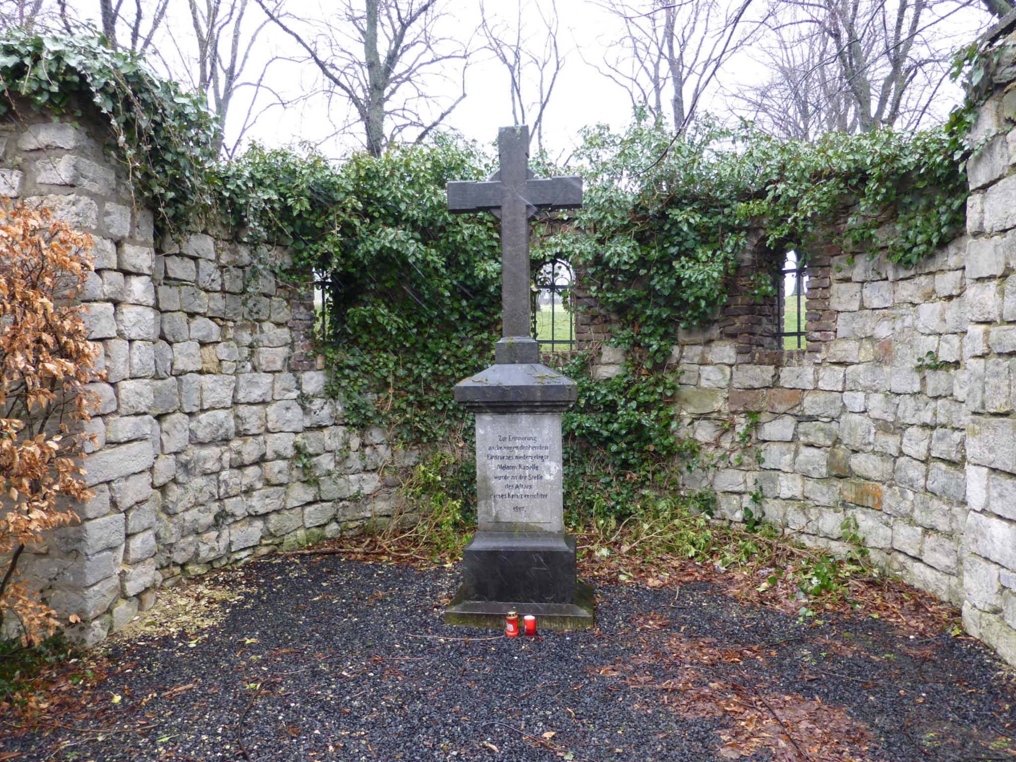 Wegekreuz aus Stein in einer gemauerten Nische am Jakobsweg Gulpen