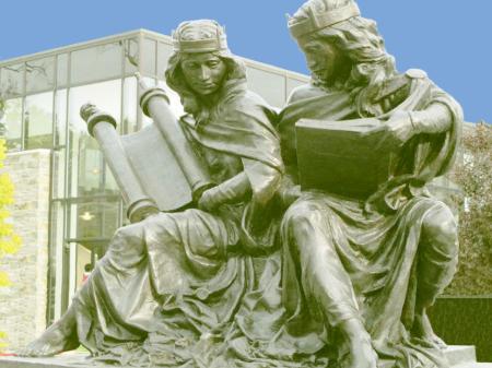 Bronzeskulptur. Nebeneinander sitzen zwei Frauen, eine mit einer Torarolle verkörpert die Synagoge, die andere mit einer Bibel verkörpert die Bibel.