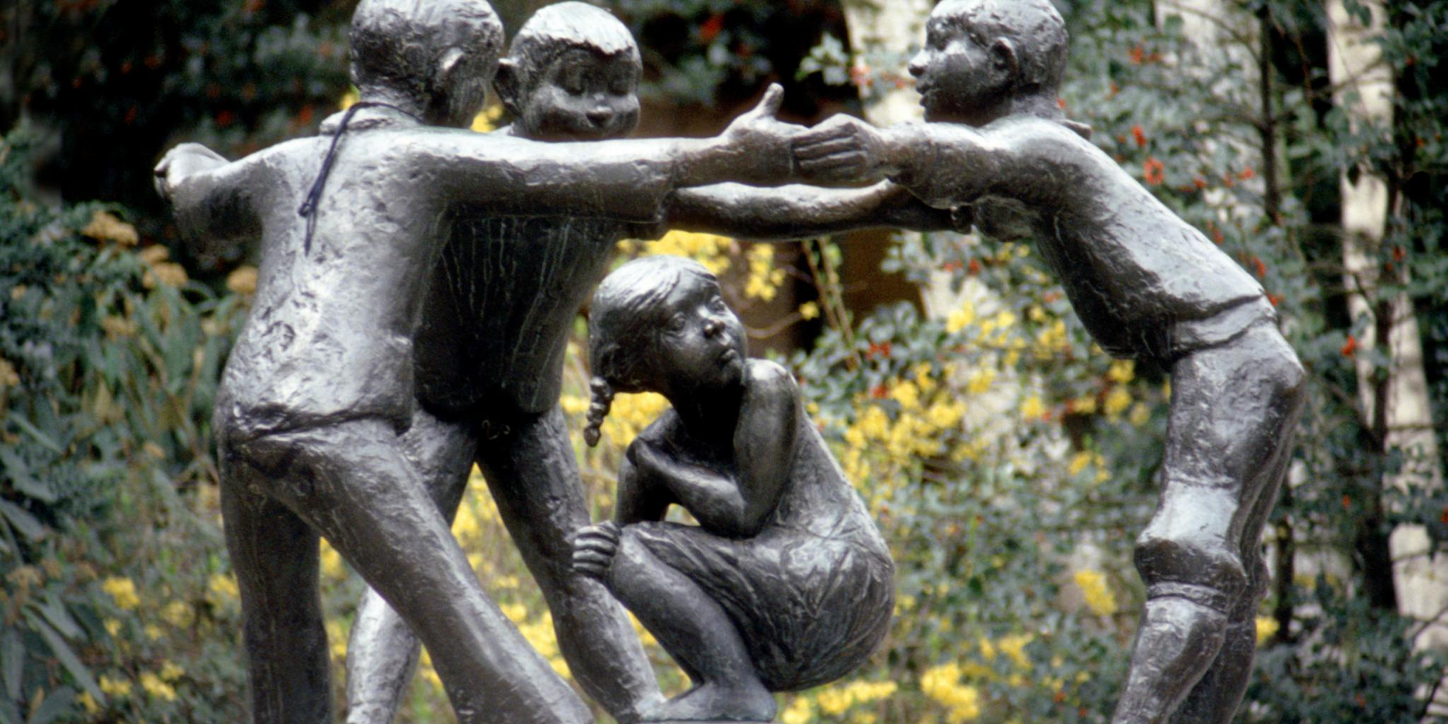 Bronzeskulptur: Drei Jungen stehen im Kreis, halten sich an den Händen im Kreis um ein Mädchen. Das hockt am Boden und kann nicht weglaufen. Das Denkmal ist nach dem Lied 'Türelüre-Lißje' geschaffen.