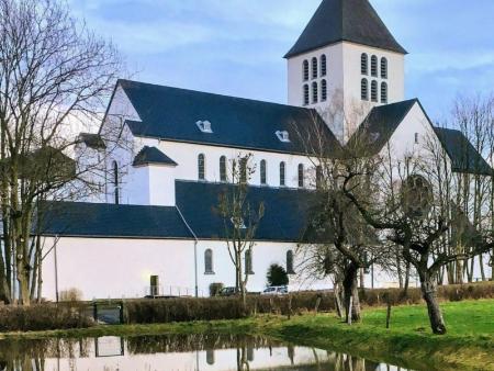 Benediktinerabtei Kornelimünster (c) Kirchenzeitung für das Bistum Aachen Ein Klostergebäude mit Kirchenschiff und Kirchturm inmitten eines Gartens mit einem kleinen Weiher davor.