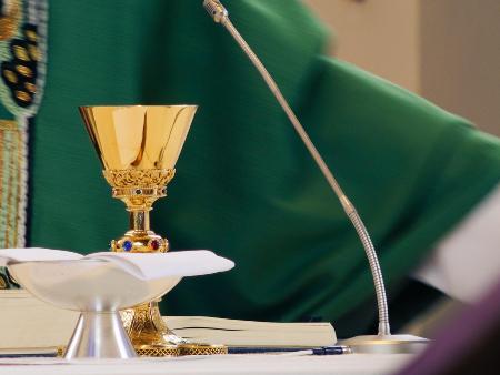 Priester beim Hochgebet (c) Sebastian Strauch/Pixabay.com Auf dem Altar stehen Kelch und Patene, dahinter sieht man einen Teil eines Priesters im grünen Messgewand.