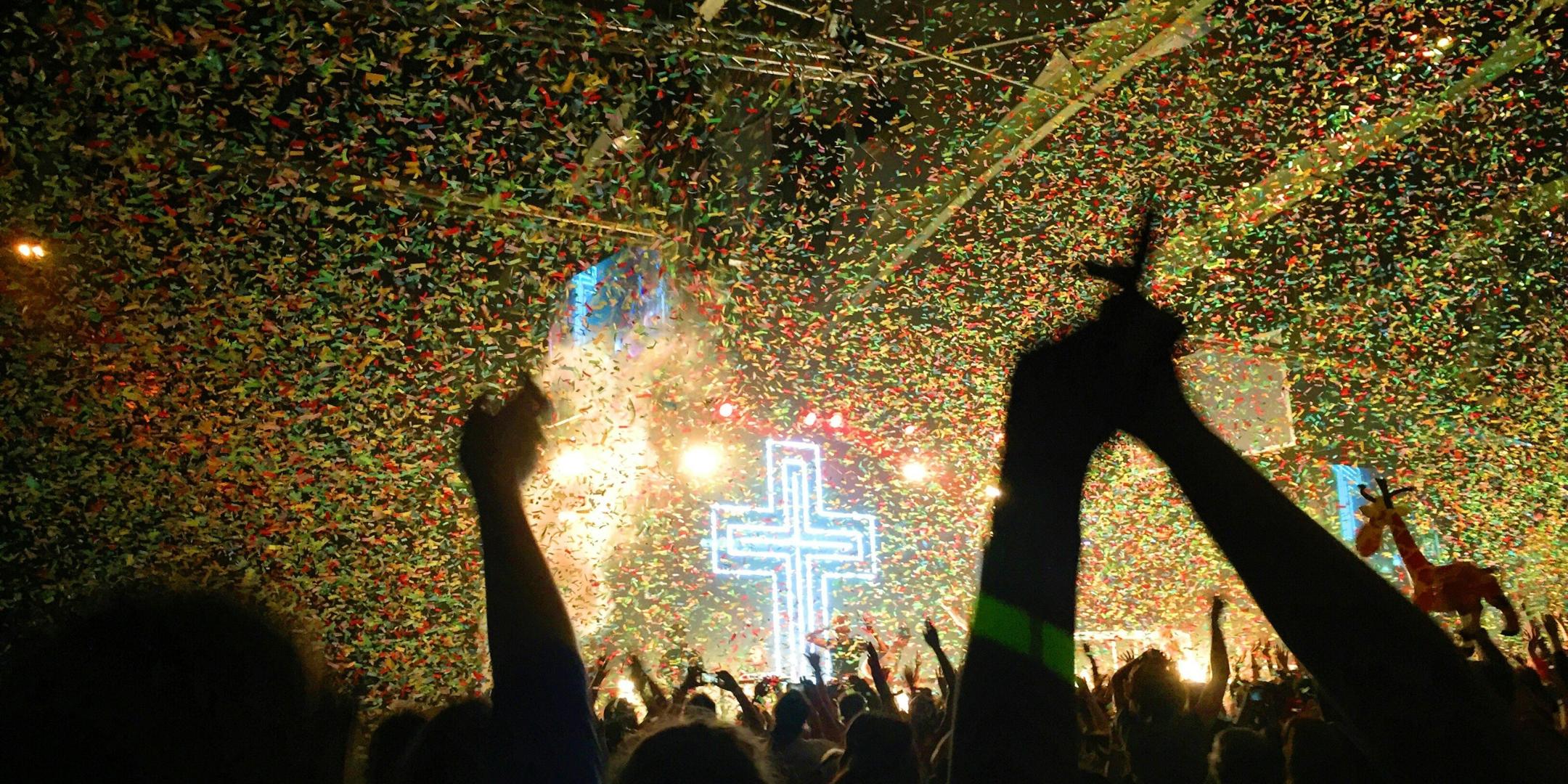 Ein erleuchtetes Kreuz, davor eine Menge von Menschen, einige mit erhobenen Armen.