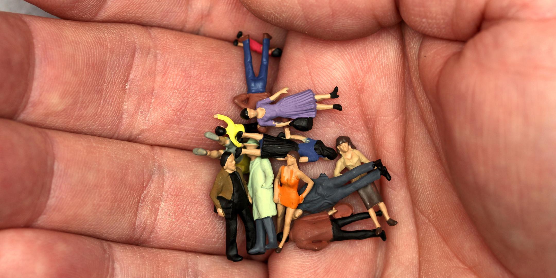 Kleine Spielfiguren (Männer, Frauen, verschiedene Personen) liegen auf einer Handfläche