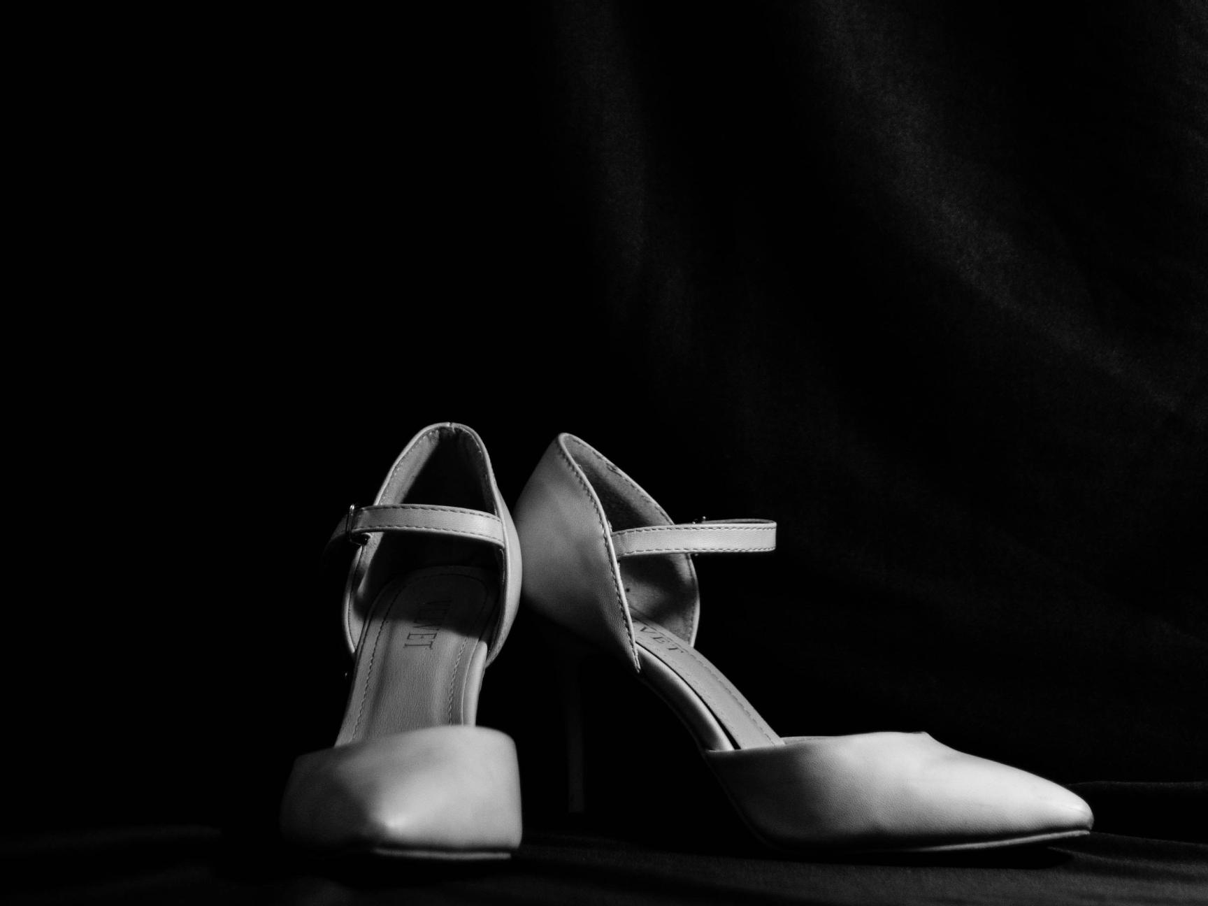 Ein Paar Frauenschuhe, hohe Pumps, vor schwarzem Hintergrund.