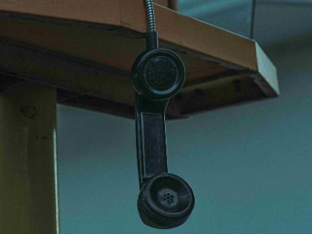 Hörer eines alten Telefons hängt von einem Tisch herunter.