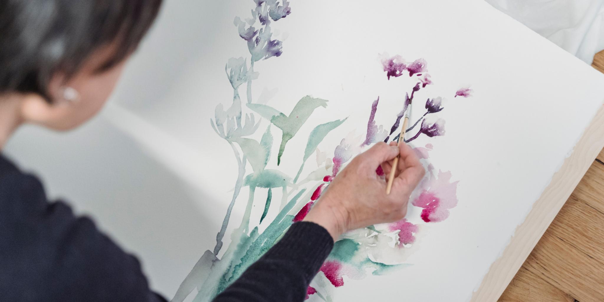 Frau malt Pflanzen in Aquarelltechnik.