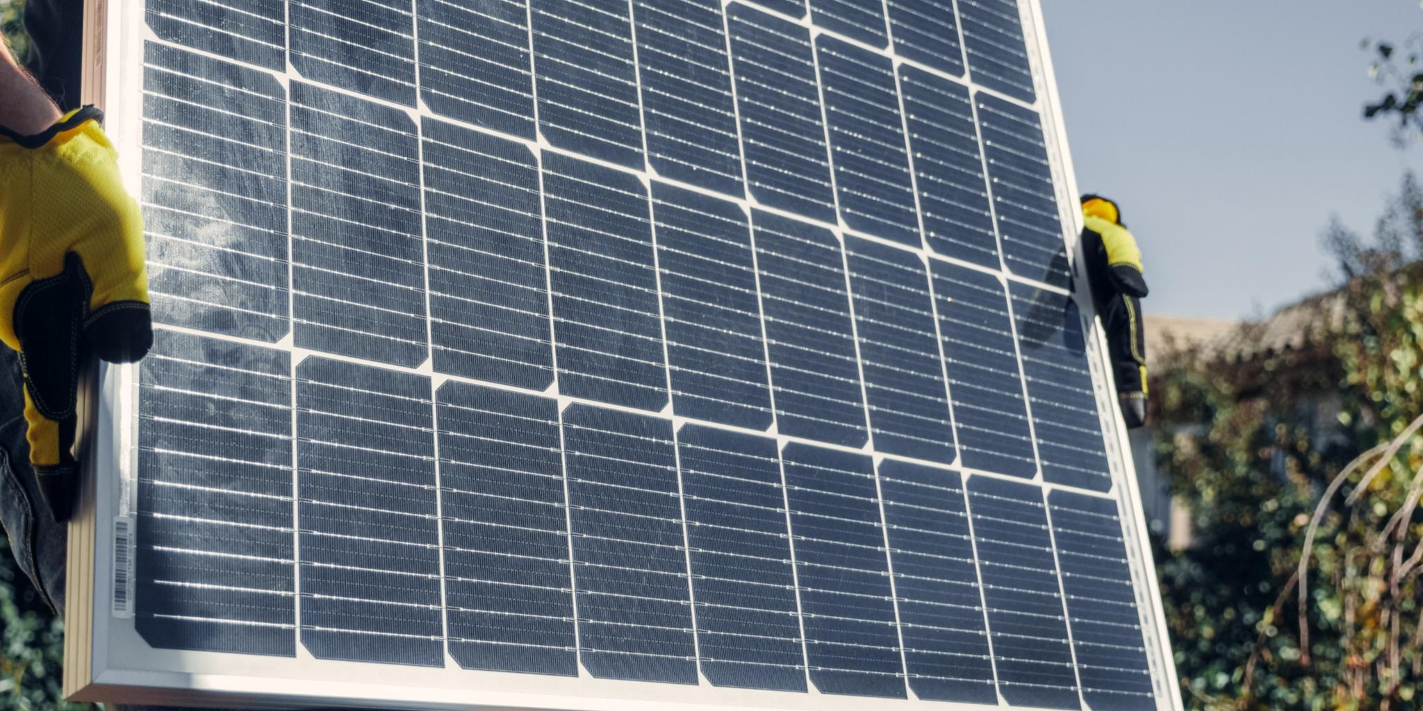 Hände in Arbeitshandschuhen halten Solarpanel