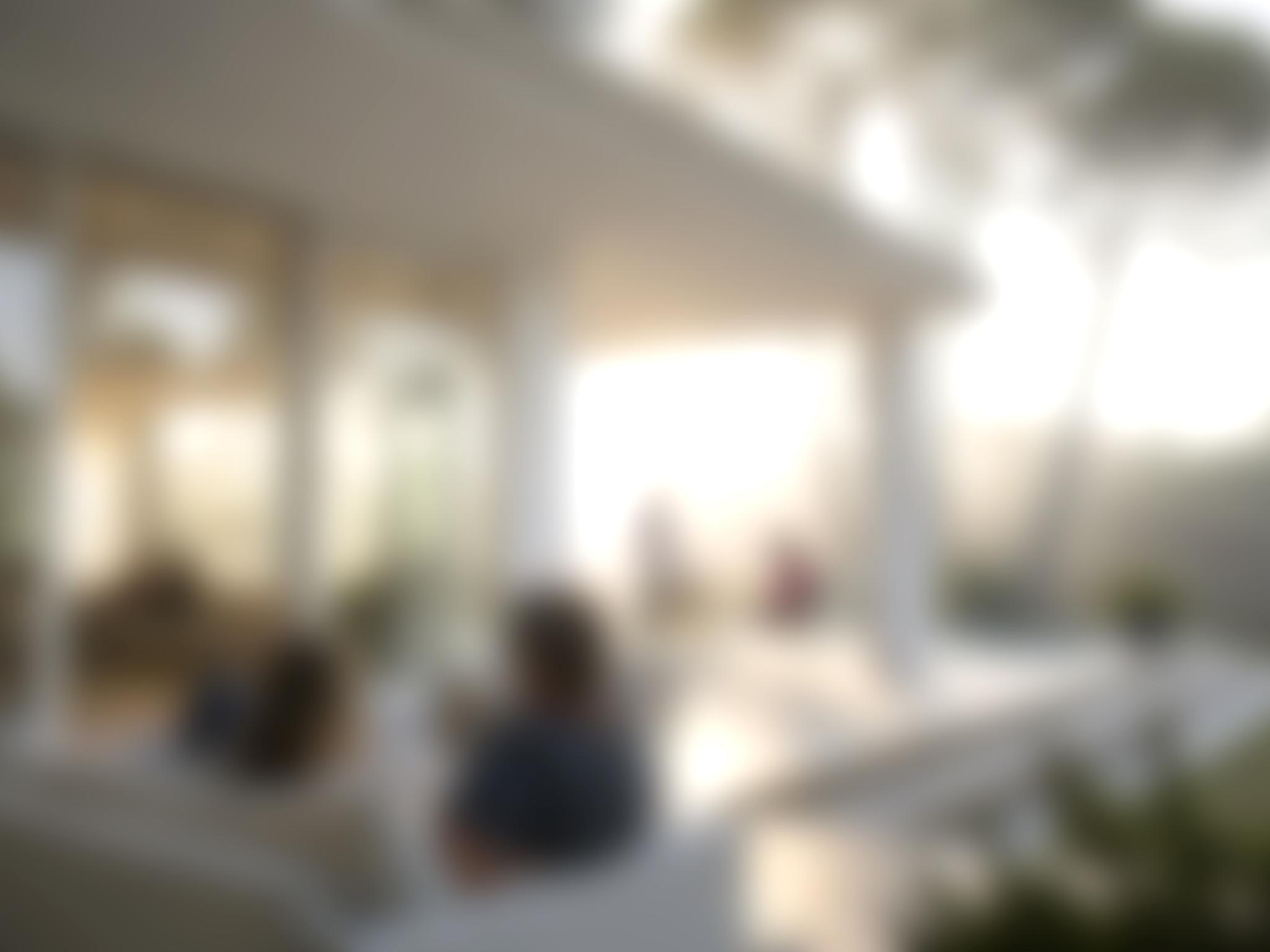 Sehr verschwommenes Bild, man ahnt Menschen miteinander im Gespräch, dahinter Palmen.